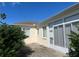 Back patio with mature hedges and enclosed lanai featuring many windows at 5500 Nw 23Rd Pl, Ocala, FL 34482