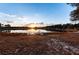 Lake view from the backyard, featuring a wooden dock, golden hour sunset, and lush trees at 5526 Se 170Th Ct, Ocklawaha, FL 32179