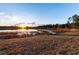 Lakeside backyard showcasing a wooden dock, sunset reflecting off the water, and natural landscaping at 5526 Se 170Th Ct, Ocklawaha, FL 32179