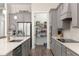 Modern kitchen with gray cabinetry, stainless steel appliances, quartz countertops, and a view into the pantry at 5728 Sw 90Th Court Rd, Ocala, FL 34481