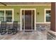 Inviting front porch with tiled flooring, stone pillars, and traditional rocking chairs at 5995 Se 22Nd Ave, Ocala, FL 34480