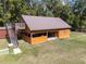 Exterior view of orange outbuilding with stairs leading to a deck and partially open front at 5995 Se 22Nd Ave, Ocala, FL 34480