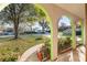 View from the arched porch showcasing the spacious front yard, mature trees, and neighboring house at 711 Se 26Th St, Ocala, FL 34471