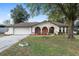 Charming single-story home featuring unique brick accents, arched entryways, mature trees, and an attached two-car garage at 711 Se 26Th St, Ocala, FL 34471