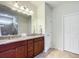 A bathroom features wooden vanity, tiled floors, a large mirror and modern lights at 9697 Sw 63Rd Loop, Ocala, FL 34481