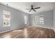 Primary bedroom with hardwood floors, a ceiling fan, and lots of natural light from three windows at 10138 Lake Miona Way, Oxford, FL 34484