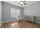 Bright bedroom with wood floors, ceiling fan, crib, and glider at 10138 Lake Miona Way, Oxford, FL 34484