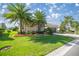 Well-maintained home with lush landscaping, including palm trees, and a brick driveway at 10138 Lake Miona Way, Oxford, FL 34484