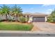 Beautiful home featuring a two-car garage, manicured lawn, mature palm trees, and brick-paved driveway at 10138 Lake Miona Way, Oxford, FL 34484