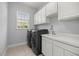 Bright laundry room with washer, dryer, sink, and ample storage cabinets at 10138 Lake Miona Way, Oxford, FL 34484