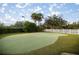 Lush putting green with manicured landscaping, framed by a white picket fence at 10138 Lake Miona Way, Oxford, FL 34484