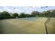 Well-kept tennis court surrounded by lush green landscaping and mature trees at 10138 Lake Miona Way, Oxford, FL 34484