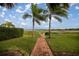 Scenic waterfront view featuring a brick walkway lined with palm trees and manicured lawn leading to a tranquil lake at 10138 Lake Miona Way, Oxford, FL 34484
