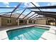 A sparkling pool reflects a blue sky within the screened-in enclosure of a home's back yard at 10215 Sw 134Th Ct, Dunnellon, FL 34432