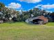 Home's exterior with a carport and green lawn under a blue sky with scattered clouds at 13521 N Magnolia Ave, Citra, FL 32113