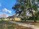 A long shot of a home with solar panels, a covered porch, and outbuildings, framed by mature trees and a long driveway at 13521 N Magnolia Ave, Citra, FL 32113