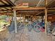 Cluttered shed featuring fitness equipment, bikes, and miscellaneous items under a rustic wooden beam roof at 13521 N Magnolia Ave, Citra, FL 32113