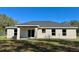 Backyard exterior showcasing the home with sliding glass doors and large windows at 13936 Sw 113 Ln, Dunnellon, FL 34432