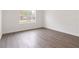 A modern bedroom with wood-look floors, white walls, and a window overlooking the neighborhood at 14404 Sw 19Th Pl, Ocala, FL 34481