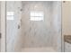 Shower with marble-look tiling, pebble floor, a window, and a shower niche for storage at 14404 Sw 19Th Pl, Ocala, FL 34481