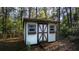 View of a shed with wood trim doors and windows, secluded among mature trees at 20260 Sw 95Th St, Dunnellon, FL 34431