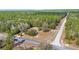 Aerial view shows this home on a spacious lot with a long driveway, surrounded by trees at 23761 Sw Plaza Ct, Dunnellon, FL 34431