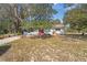 Charming single-story home with a red metal roof, red front door, and mature trees at 23761 Sw Plaza Ct, Dunnellon, FL 34431