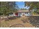 Charming single-story home with a red metal roof, bright red doors, set amidst mature trees at 23761 Sw Plaza Ct, Dunnellon, FL 34431