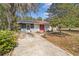 Charming single-story home with a red metal roof, bright red doors, and mature landscaping at 23761 Sw Plaza Ct, Dunnellon, FL 34431