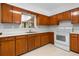 Efficient kitchen with wood cabinets, white appliances, and a window overlooking the yard at 23761 Sw Plaza Ct, Dunnellon, FL 34431