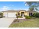 Charming yellow single Gathering home with a two-car garage, a well-manicured lawn and blue sky at 3001 Rugby Way, The Villages, FL 32162