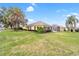 Scenic view of the yellow home with a screened lanai, lush greenery, and mature trees in the backyard at 3001 Rugby Way, The Villages, FL 32162