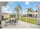 Screened patio offers outdoor dining with a table and chairs, surrounded by well-maintained landscaping at 3001 Rugby Way, The Villages, FL 32162