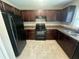 Well-lit kitchen featuring dark cabinets, modern appliances, and tiled floors at 3044 Sw 168Th Loop, Ocala, FL 34473