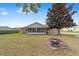 Backyard view featuring a screened-in sunroom, a fire pit, and lush green grass, perfect for entertaining at 4837 Ne 5Th Street Rd, Ocala, FL 34470