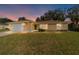 Charming single-story home with a well-manicured lawn, attached garage, and neutral stucco exterior at dusk at 4837 Ne 5Th Street Rd, Ocala, FL 34470