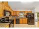 Eat-in kitchen featuring wooden cabinetry, tile backsplash, and black appliances at 4837 Ne 5Th Street Rd, Ocala, FL 34470