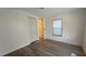 Bright bedroom features wood-look flooring, neutral walls, a closet, and a window for natural light at 615 Ne Cottage Park Ln, Leesburg, FL 34748