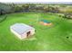 Aerial view of a fenced in pasture containing a barn and long building with a green roof at 6994 Nw 320 Hwy, Micanopy, FL 32667