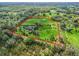 Overhead view of estate featuring lush pastures outlined in red, mature trees, and residence at 6994 Nw 320 Hwy, Micanopy, FL 32667