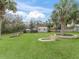 Expansive backyard with lush lawn, palm trees, outbuildings, and a brick-lined firepit at 6994 Nw 320 Hwy, Micanopy, FL 32667