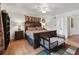 Main bedroom features a dark wood bed frame, hardwood floors, ceiling fan, and ensuite bathroom at 6994 Nw 320 Hwy, Micanopy, FL 32667