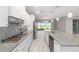 Modern kitchen with white cabinets, granite countertops, and stainless steel appliances, adjacent to a bright living area at 8107 Sw 92Nd Cir, Ocala, FL 34481