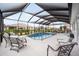 A covered lanai features a modern pool, cushioned seating, and a dining table for luxury outdoor living at 9270 Sw 89Th Street Rd, Ocala, FL 34481