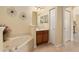 Bright bathroom featuring a soaking tub, vanity with a brown cabinet, and neutral tiling at 9274 Sw 94Th Loop, Ocala, FL 34481