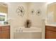 This bathroom highlights a marble-like tub with decor and a pair of vanities on either side at 9274 Sw 94Th Loop, Ocala, FL 34481