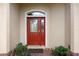 Close-up of a decorative red front door with glass inserts, framed by potted plants and a brick-paved entrance at 9274 Sw 94Th Loop, Ocala, FL 34481