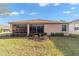 A view of the backyard, featuring a glass sunroom, flowerbeds and well-maintained lawn at 1029 Sw 157Th Ln, Ocala, FL 34473