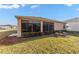 A view of the backyard, featuring a glass sunroom, flowerbeds and well-maintained lawn at 1029 Sw 157Th Ln, Ocala, FL 34473