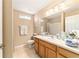 Comfortable bathroom featuring a wood vanity, neutral tile flooring and walls, and a decorative mirror with lighting at 1029 Sw 157Th Ln, Ocala, FL 34473